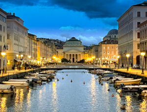 Grand Canal of Trieste at Twilight, reflecting the city's Venetian influence with illuminated waterfront buildings and calm waters