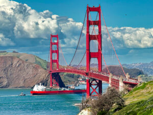 Golden freighter passing beneath the Golden Gate Bridge.
